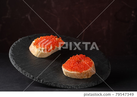 Sandwiches with red caviar on a black tray. Serving caviar sandwiches. Red and black. 79547349
