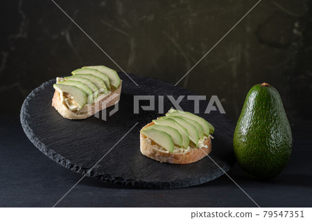 Sliced avocado into wedges. Avocado slices and a whole vegetable. Showcase with sandwiches. 79547351