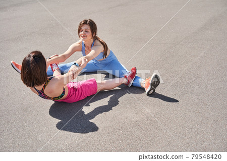 Midget woman holding hands of her best friend while stretching Midget woman holding hands of her best friend while stretching 79548420