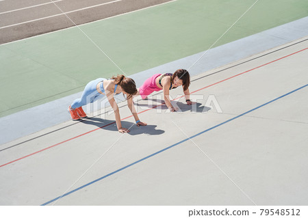 Woman doing planking exercise at the stadium at the company of her midget best friend Woman doing planking exercise at the stadium at the company of her midget best friend 79548512