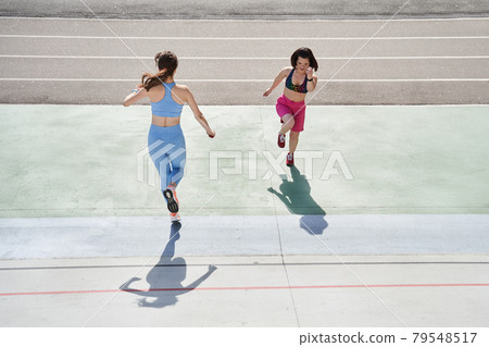 Two girls running and exercising at the sunny morning at the stadium 79548517