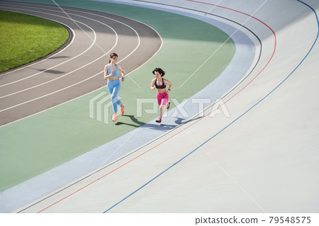 Midget woman running on the stadium with her best friend Midget woman running on the stadium with her best friend 79548575