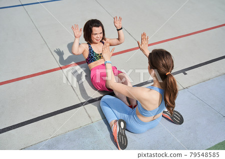 Best friends clapping at the hands while pumping abdominal muscles on the stadium Best friends clapping at the hands while pumping abdominal muscles on the stadium 79548585