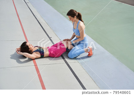 Best friends pumping abdominal muscles on the stadium at the morning Best friends pumping abdominal muscles on the stadium at the morning 79548601