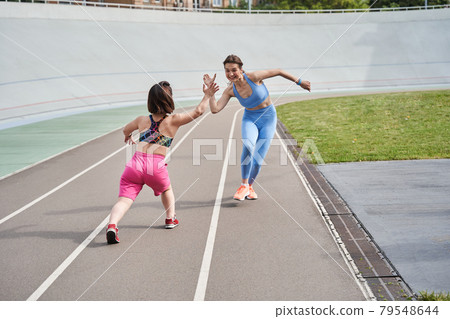 Midget girl waiting at the finish and giving five to her best friend while she running Midget girl waiting at the finish and giving five to her best friend while she running 79548644