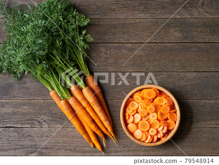 chopped carrots in a wooden bowl on a table, top view. chopped carrots in a wooden bowl on a table, top view. 79548914