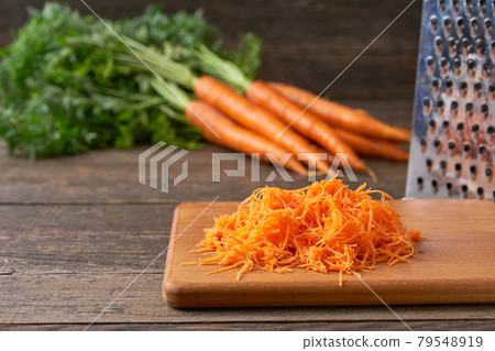 Fresh grated carrots on a cutting board, selective focus. Fresh grated carrots on a cutting board, selective focus. 79548919