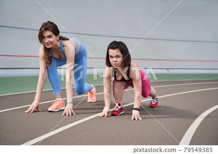 Sporty girls are ready to run on the racetrack at the stadium Sporty girls are ready to run on the racetrack at the stadium 79549385