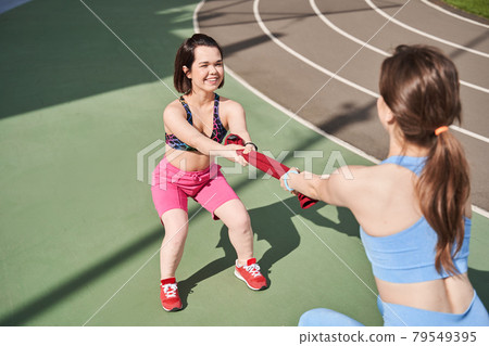 Girls standing in front of each other while tug of towel like a war Girls standing in front of each other while tug of towel like a war 79549395