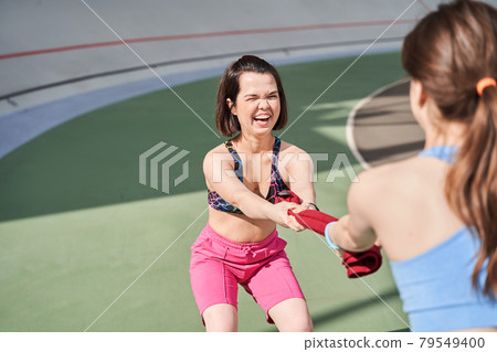 Woman laughing out loud while tug of towel like a war with her best friend 79549400