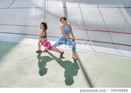 Couple of best friends or fitness partners stretching and warming up Couple of best friends or fitness partners stretching and warming up 79549408