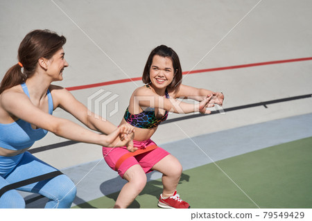 Women squat on the grass at the stadium while rejoicing of the time with each other Women squat on the grass at the stadium while rejoicing of the time with each other 79549429