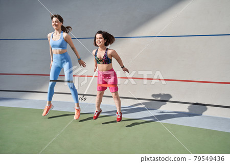 Midget woman wearing sports wear exercising in outdoor arena with her best friend Midget woman wearing sports wear exercising in outdoor arena with her best friend 79549436
