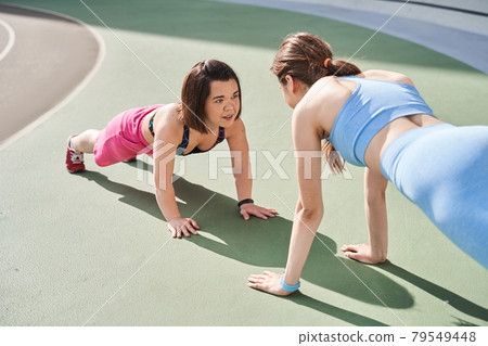Diverse girls standing at the plank position at the morning at the stadium Diverse girls standing at the plank position at the morning at the stadium 79549448