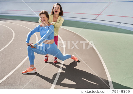 Midget caucasian woman laughing out loud while helping to her best friend doing lunges 79549509