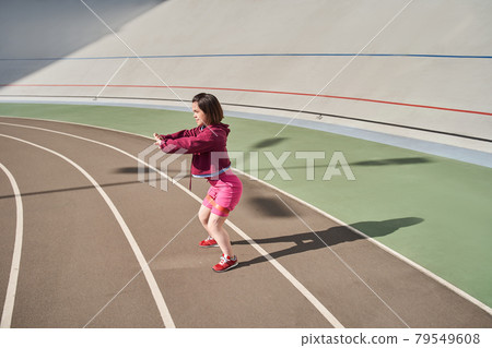 Midget woman squatting at the stadium outdoor during the morning 79549608