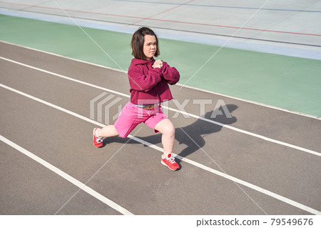 Midget woman doing stretching at the stadium at the morning 79549676