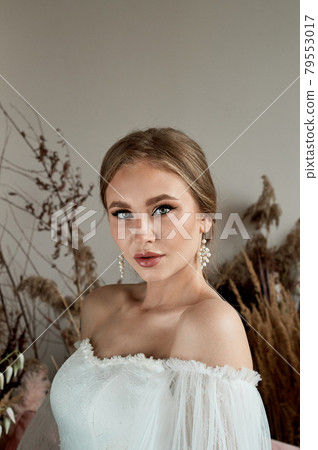 Portrait of the bride in a white dress with open shoulders. Tanned skin. Professional makeup. Portrait of the bride in a white dress with open shoulders. Tanned skin. Professional makeup. 79553017