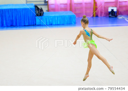 cute kid, girl is engaged in sport, she is in motion jumping over in the air cute kid, girl is engaged in sport, she is in motion jumping over in the air 79554434