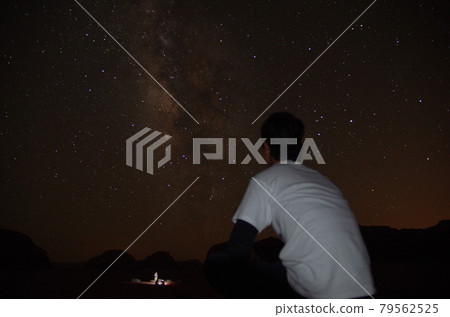 [Jordan] A man looking at the starry sky at midnight in the vast desert Wadiram 79562525