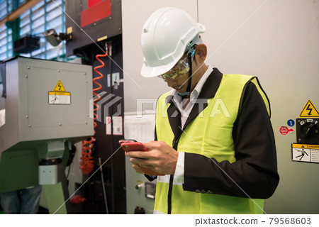 Busy factory manager check smartphone at machine Busy factory manager check smartphone at machine 79568603