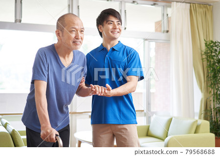 A caregiver who assists the elderly in walking 79568688