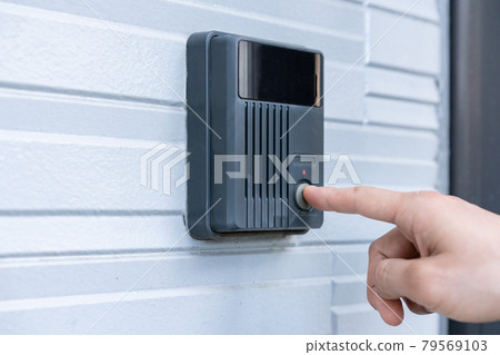 Finger pushing the doorbell on the front door Finger pushing the doorbell on the front door 79569103