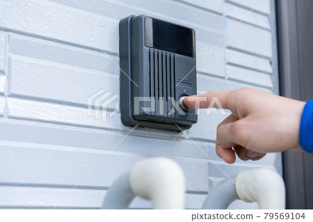Finger pushing the doorbell on the front door 79569104