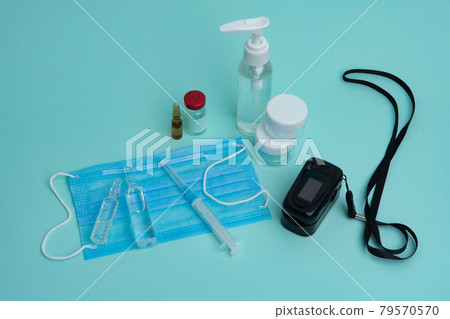 Pulse oximeter, mask, coronavirus vaccine and syringe on a blue background. Diagnosis of Covid 19. 79570570