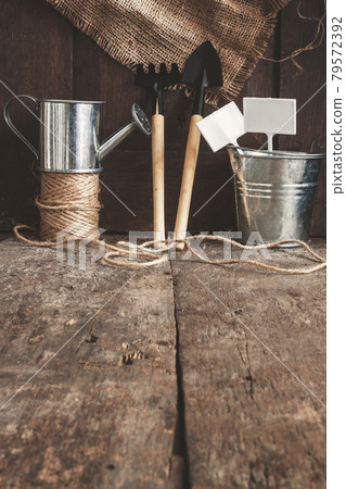 Garden tool, shovel, rake, watering can, bucket, bag on a wooden old brown background, close-up Garden tool, shovel, rake, watering can, bucket, bag on a wooden old brown background, close-up 79572392