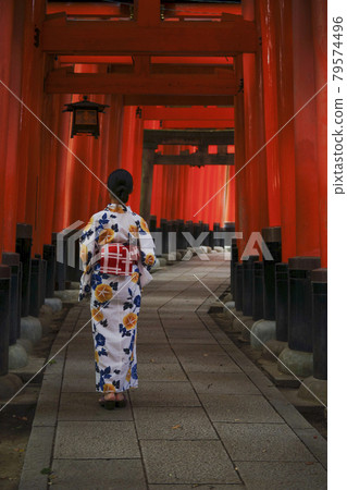 A young woman in a yukata under the red torii gate of Fushimi Inari Shrine A young woman in a yukata under the red torii gate of Fushimi Inari Shrine 79574496