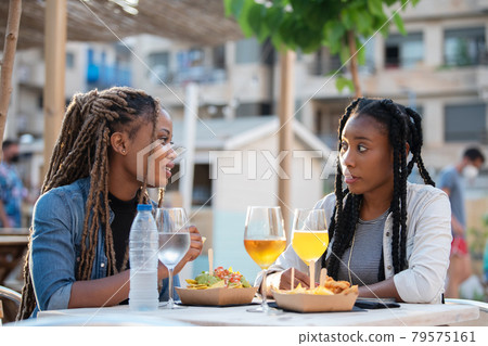Talkative afro american women with food and drinks outdoors Talkative afro american women with food and drinks outdoors 79575161