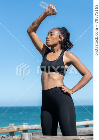 Tired latin american woman refreshing herself with water after exercising: Health concept. Tired latin american woman refreshing herself with water after exercising: Health concept. 79575165