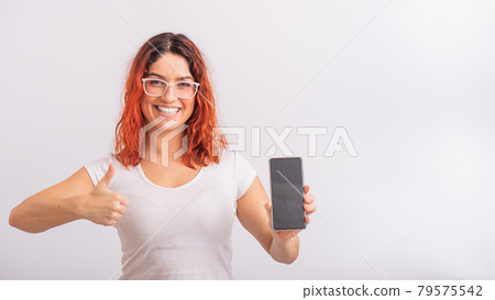 Caucasian woman holding phone with blank screen and showing thumb up on white background. Caucasian woman holding phone with blank screen and showing thumb up on white background. 79575542