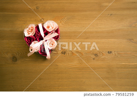 Top view of flowers in a heart box on a wooden table. heart box with roses. Rose petals in heart-shaped box on wooden table. 79581259
