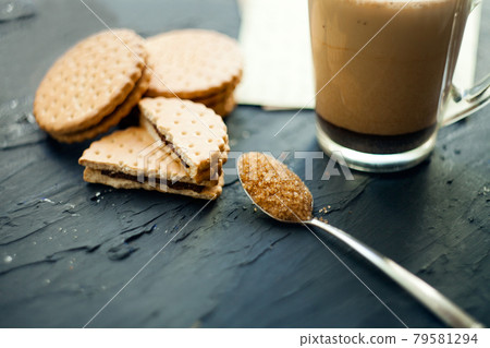 Cup of Coffee with a Cookies and brown shugar. Symbolic image. Coffee background. Sweet dessert. Wooden background. Close up. Freshly brewed cup of cafe latte coffee served with chocolate cookies in a 79581294