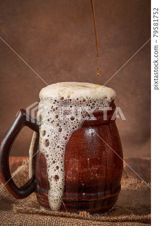 Beer clay brown mug with kvass on a wooden table on a dark background. A traditional drink made of bread, sourdough 79581752
