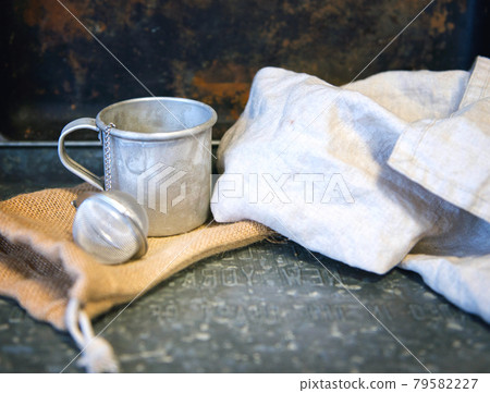 Metal teacup with tea egg behind the cotton white towel. rustic vintage style 79582227