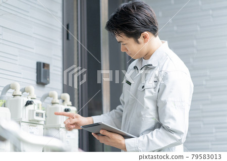 一名年輕男工在獨立屋前檢查儀表 79583013