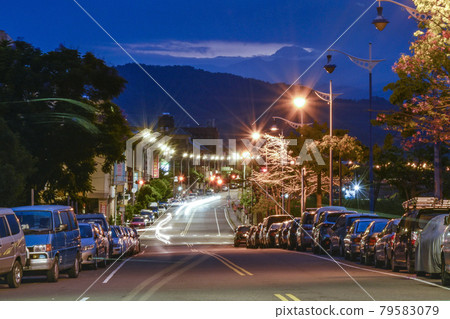 天藍色的色調,遠山雲層之上的微弱晨曦,火車在長長的道路上一字排開,路邊的燈光閃爍。 天藍色的色調,遠山雲層之上的微弱晨曦,火車在長長的道路上一字排開,路邊的燈光閃爍。 79583079