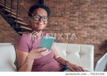 A woman in eyeglasses holding a smartphone A woman in eyeglasses holding a smartphone 79583309