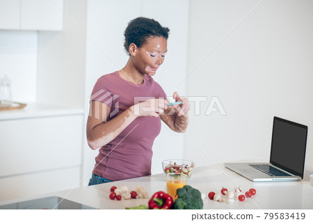 A dark-skinned woman making a picture of a salad 79583419