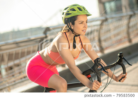 Female cyclist in bright sportswear riding a racing bike Female cyclist in bright sportswear riding a racing bike 79583500