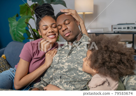 Woman hugging military husband and little girl 79583674