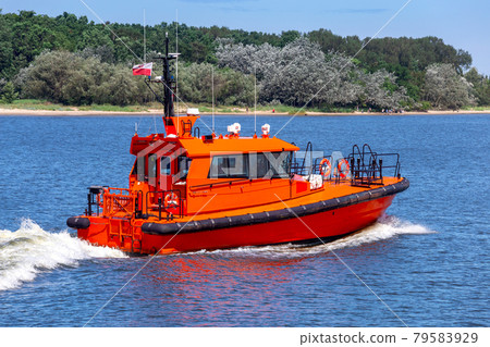 Swinoujscie. The red pilot boat goes along the river. Swinoujscie. The red pilot boat goes along the river. 79583929