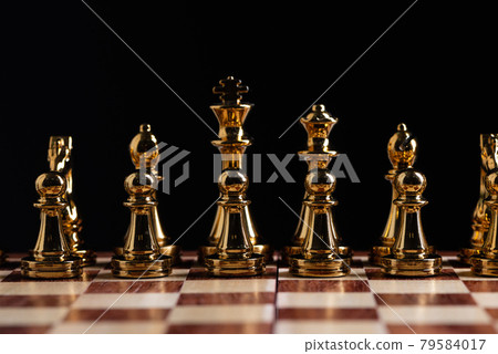 Golden chess figures standing on chessboard 79584017