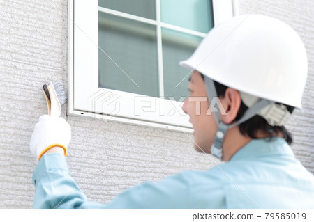Male worker painting the exterior walls of a house 79585019