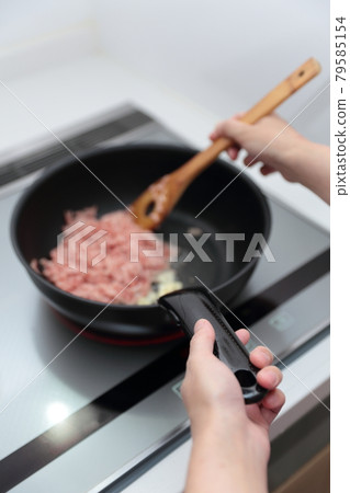 Housewife woman cooking with a frying pan on an IH cooking heater Housewife woman cooking with a frying pan on an IH cooking heater 79585154