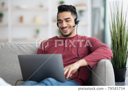 Happy arab guy attending online webinar, using laptop and headset Happy arab guy attending online webinar, using laptop and headset 79585734