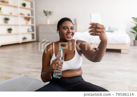 Curvy African American woman taking selfie on break from home workout, talking to personal trainer on web at home 79586114